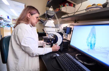 CNAS student with lab coat and microscope